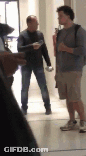 Two Men In Hallway One Holding Water Bottle GIF