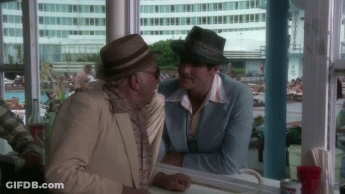 Two Men In Hats Sitting At Counter Talking GIF