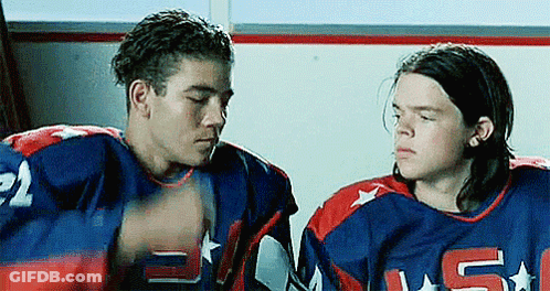 Two Men In Hockey Jerseys Sitting In Locker Room GIF