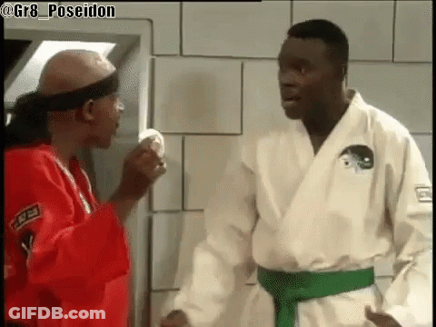 Two Men In Karate Uniforms Are Standing Next To Each Other . GIF