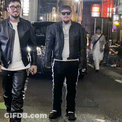 Two Men In Leather Jackets Are Walking Down The Street GIF