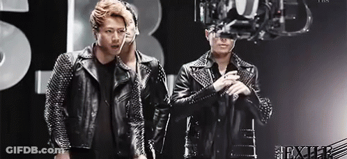 Two Men In Leather Jackets In Front Of Chandelier GIF