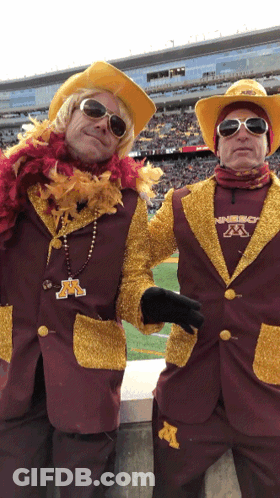 Two Men In Maroon And Gold Outfits With M GIF