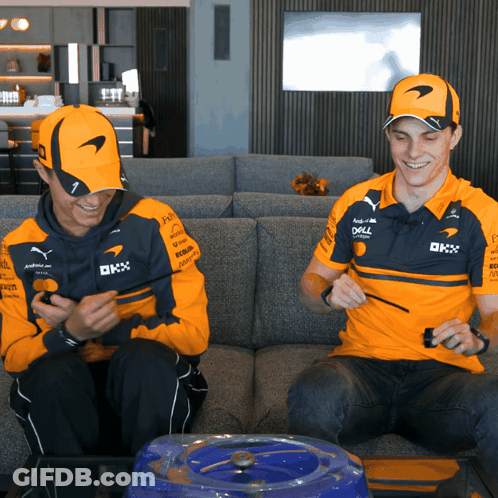 Two Men In McLaren Shirts On Couch Looking At Phones GIF