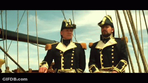 Two Men In Military Uniforms Are Standing On A Boat GIF