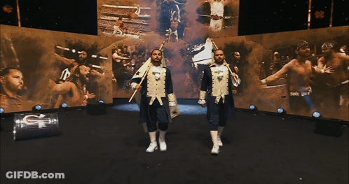 Two Men In Military Uniforms Stand In Front Of A Large Screen That Says G On It GIF