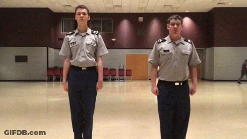 Two Men In Military Uniforms Standing GIF