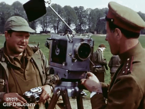 Two Men In Military Uniforms Talking In Front Of Kronos Media Camera GIF