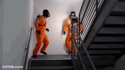 Two Men In Orange Jumpsuits Are Walking Down Stairs GIF
