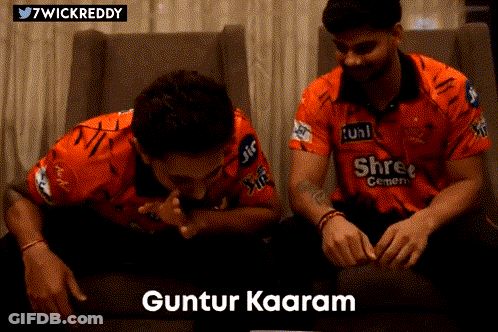 Two Men In Orange Shirts Are Sitting On A Couch And One Of Them Says Guntur Kaaram GIF