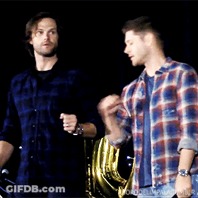 Two Men In Plaid Shirts Are Standing Next To Each Other In A Dark Room .. GIF