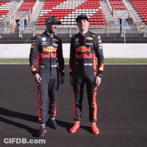 Two Men In Red Bull Racing Suits On Race Track GIF