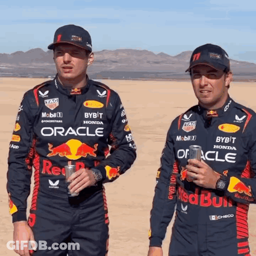 Two Men In Red Bull Racing Uniforms Standing In Desert GIF
