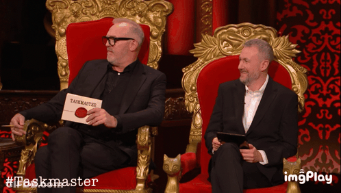 Two Men In Red Chairs With Taskmaster Sign GIF