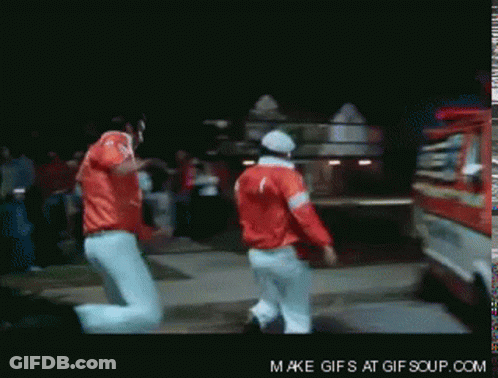 Two Men In Red Jackets Are Dancing In Front Of A Fire Truck That Says Make Gifs At Gif Soup.com GIF
