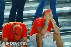 Two Men In Red Shirts Are Sitting On The Ground With Their Hands On Their Faces .. GIF
