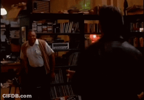 Two Men In Room With Back To The Sixties On Screen GIF