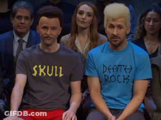 Two Men In Skull And Death Rock Shirts In Crowd GIF