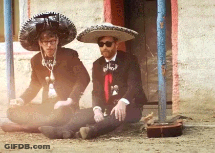 Two Men In Sombrero Hats Sitting On Ground GIF