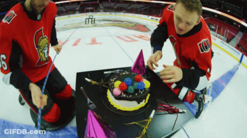 Two Men In Spartans Jerseys Decorate Birthday Cake On Ice GIF