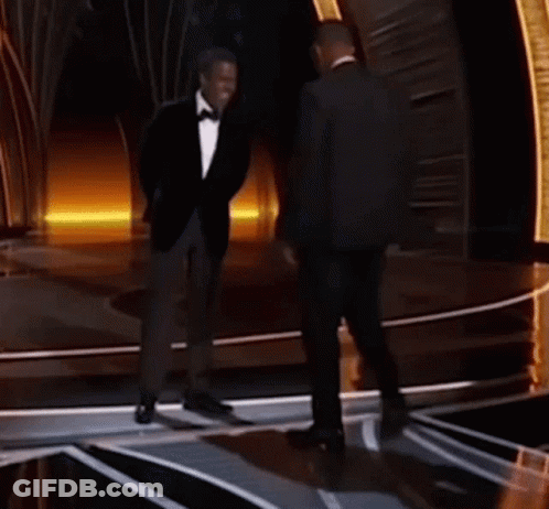 Two Men In Suits And Bow Ties Are Standing On A Stage Talking Into Microphones . GIF