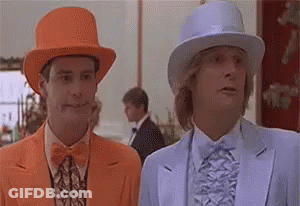 Two Men In Suits And Hats Are Standing Next To Each Other . One Of The Men Is Wearing An Orange Hat . GIF