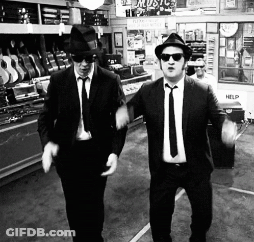 Two Men In Suits And Hats Dancing In Front Of Help Sign GIF