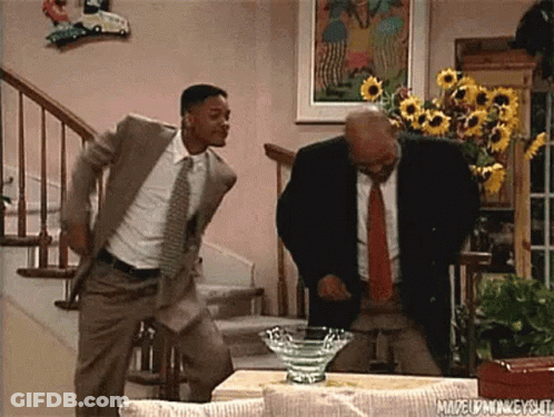 Two Men In Suits And Ties Are Dancing In A Living Room In Front Of Stairs . GIF