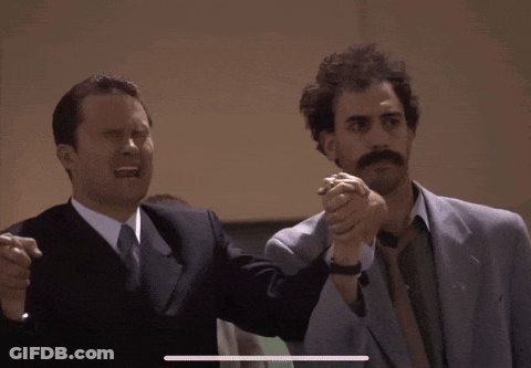 Two Men In Suits And Ties Are Holding Hands GIF