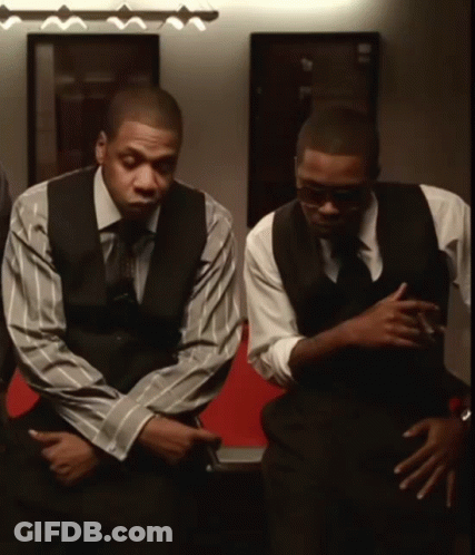 Two Men In Suits And Ties Are Sitting In A Room GIF
