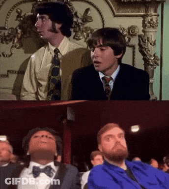 Two Men In Suits And Ties Are Sitting Next To Each Other And One Is Wearing A Blue Shirt GIF