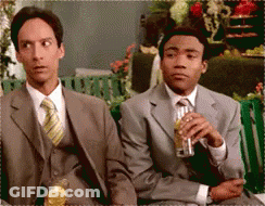 Two Men In Suits And Ties Are Sitting On A Bench Drinking Beer GIF