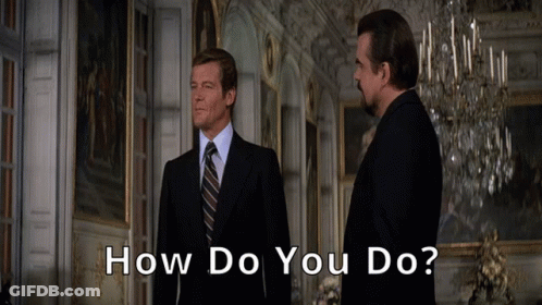 Two Men In Suits And Ties Are Standing In A Room With The Words How Do You Do Below Them GIF