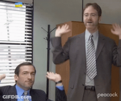Two Men In Suits And Ties Are Standing In Front Of A Window And Waving Their Hands . GIF
