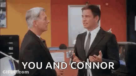 Two Men In Suits And Ties Are Standing Next To Each Other In An Office And Shaking Hands . GIF