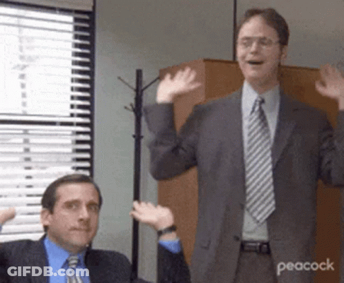 Two Men In Suits And Ties Are Waving Their Hands In A Room . GIF