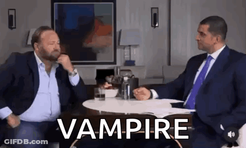 Two Men In Suits And Ties At Vampire Table GIF
