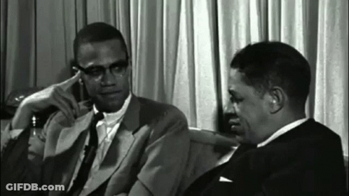 Two Men In Suits And Ties Sitting Next To Each Other GIF