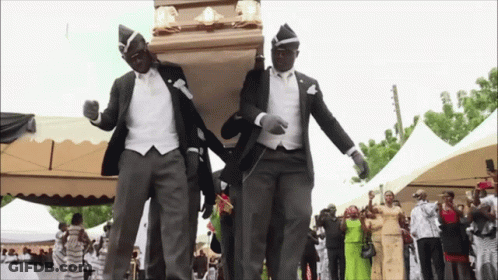 Two Men In Suits Are Carrying A Coffin While Dancing In Front Of A Crowd GIF