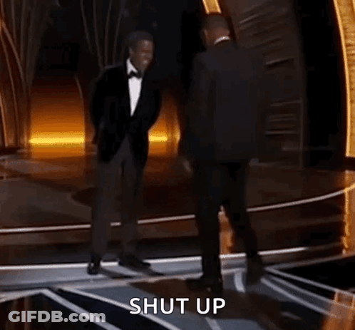 Two Men In Suits Are Dancing On A Stage And The Words Shut Up Are Visible Behind Them . GIF