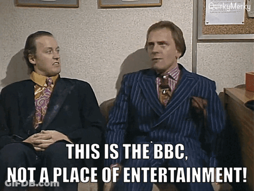Two Men In Suits Are Sitting Next To Each Other And One Of Them Says This Is The Bbc Not A Place Of Entertainment GIF
