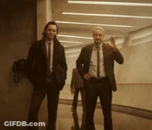 Two Men In Suits Are Standing In A Hallway GIF