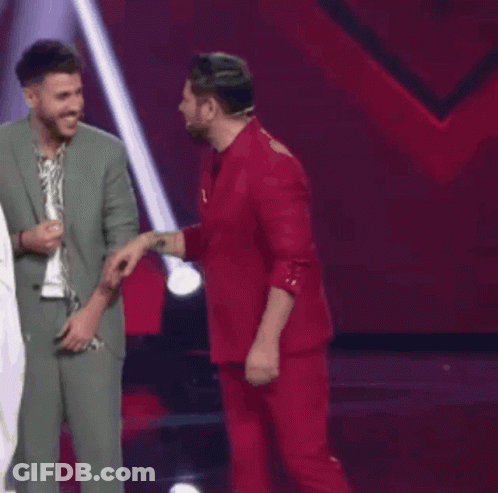 Two Men In Suits Are Standing Next To Each Other And Laughing On A Stage . GIF