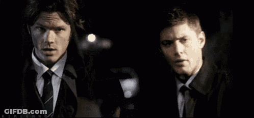 Two Men In Suits Holding Badge In Dark Room GIF