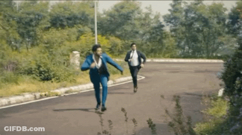 Two Men In Suits Running Down Road In Woods GIF