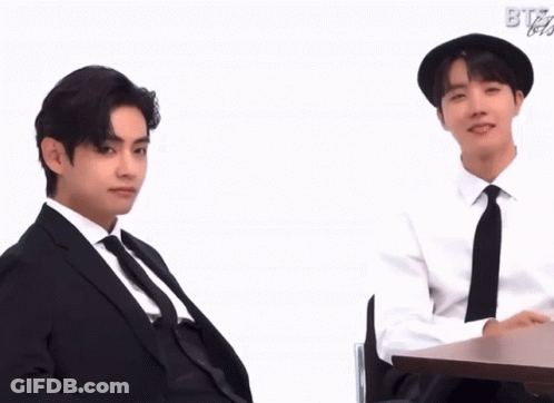 Two Men In Suits Sitting At Table With BTS GIF