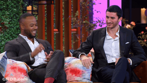 Two Men In Suits Sitting On Couch Talking GIF