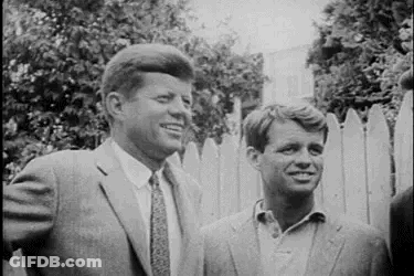 Two Men In Suits Standing By Fence GIF