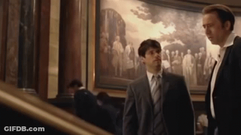 Two Men In Suits Standing In Front Of Painting GIF