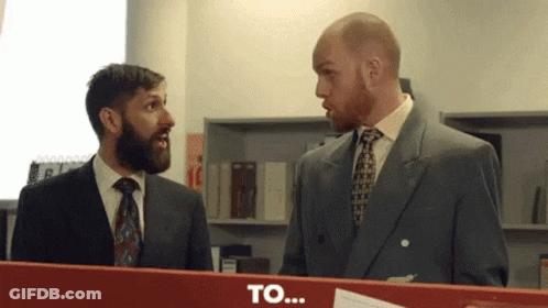 Two Men In Suits Standing Next To Each Other With Word To On Red Box GIF